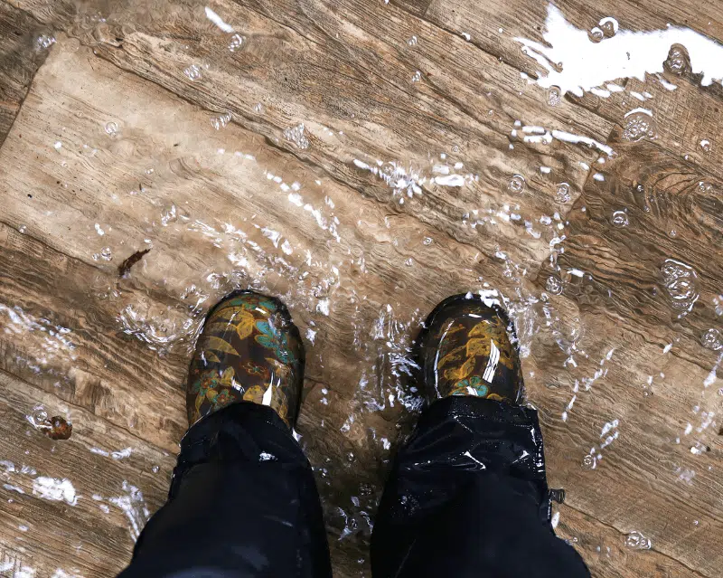 Flooded feet covered by clean water on wooden flooring